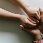 Close-up of diverse hands holding, symbolizing care, support, and friendship.